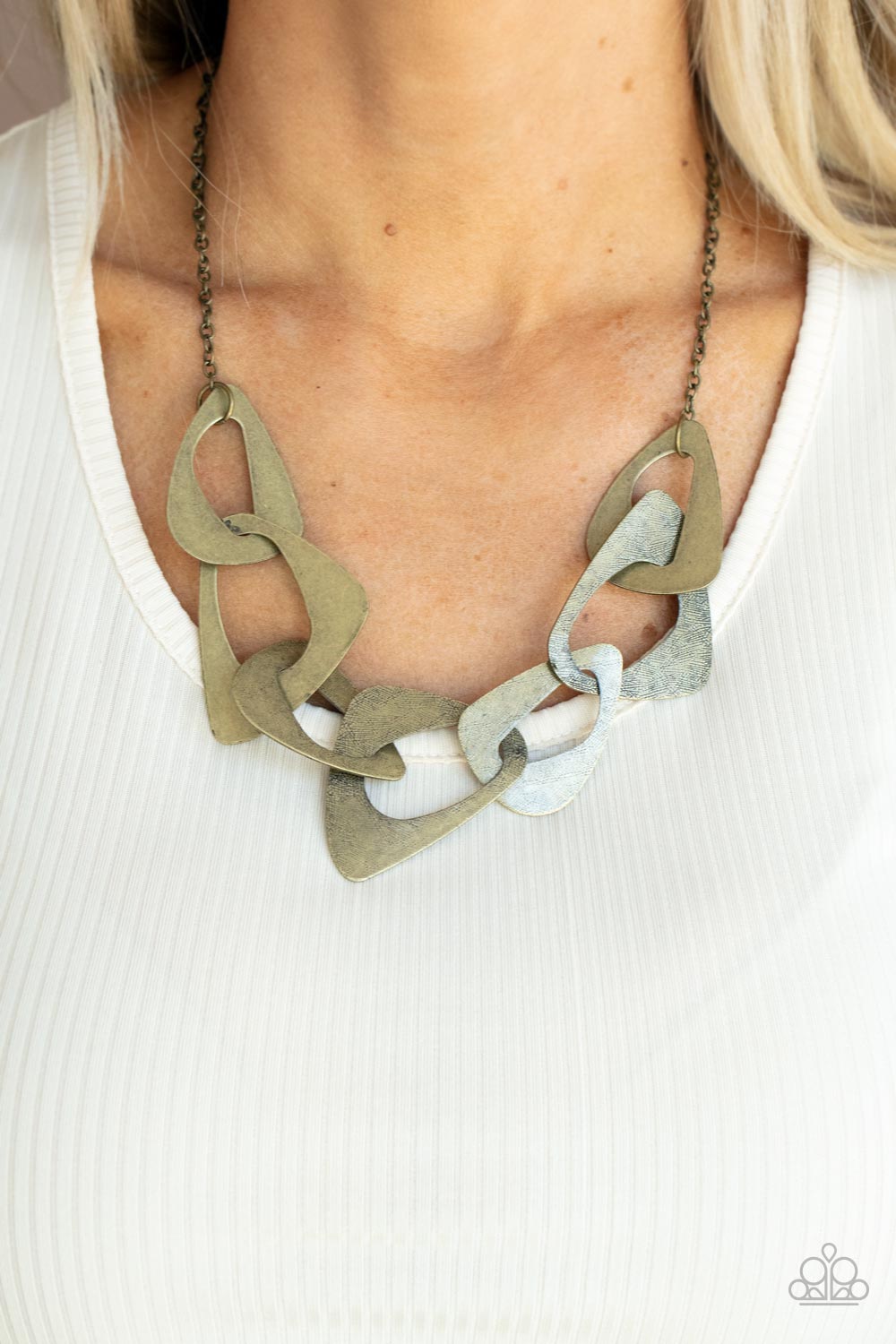 Large triangular cutouts stamped in a lightly dotted texture link below the collar forming a dramatic display of brass slices