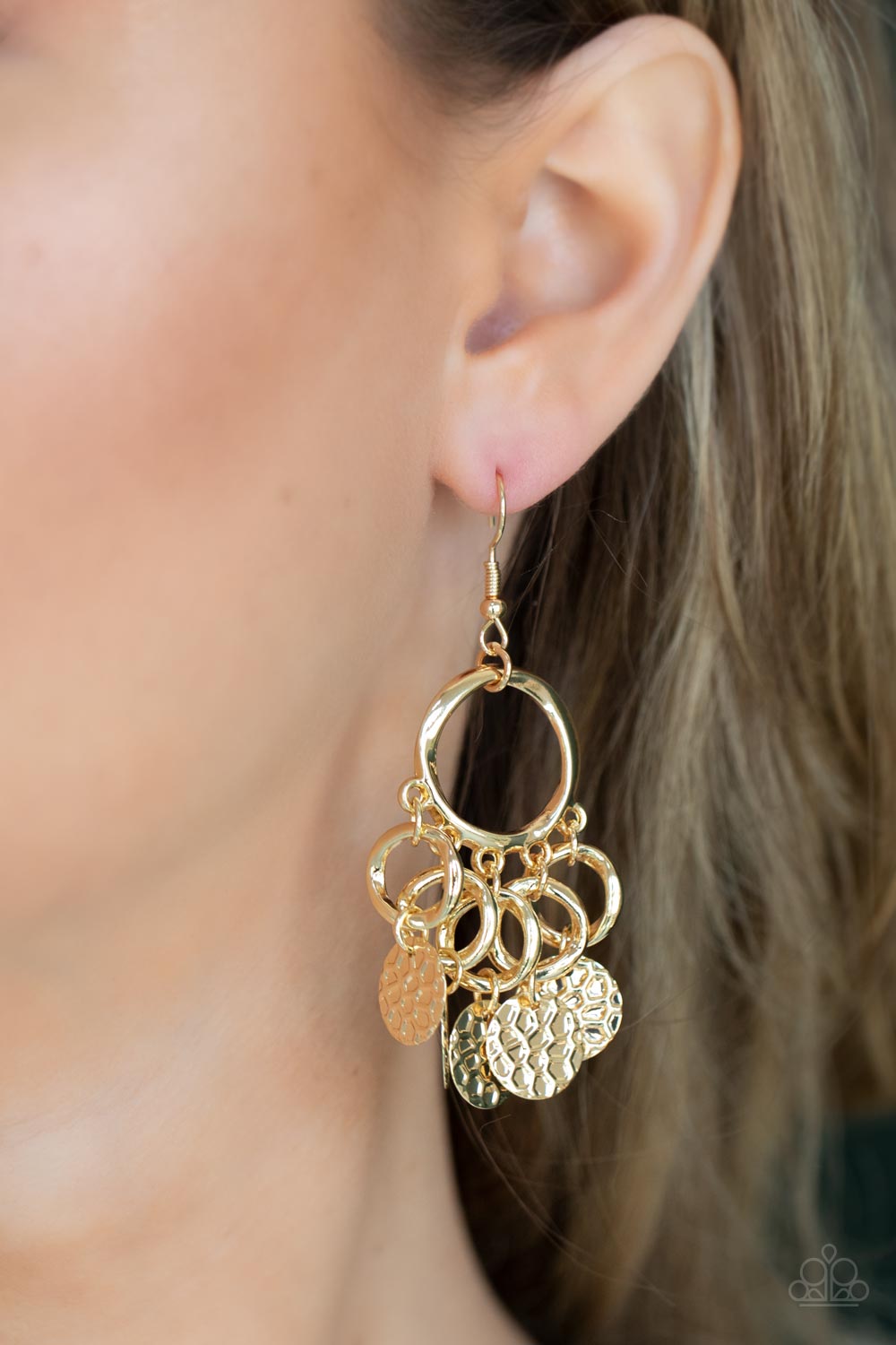 Embossed in tactile geometric patterns, shiny gold discs swing from the bottom of dainty gold rings 