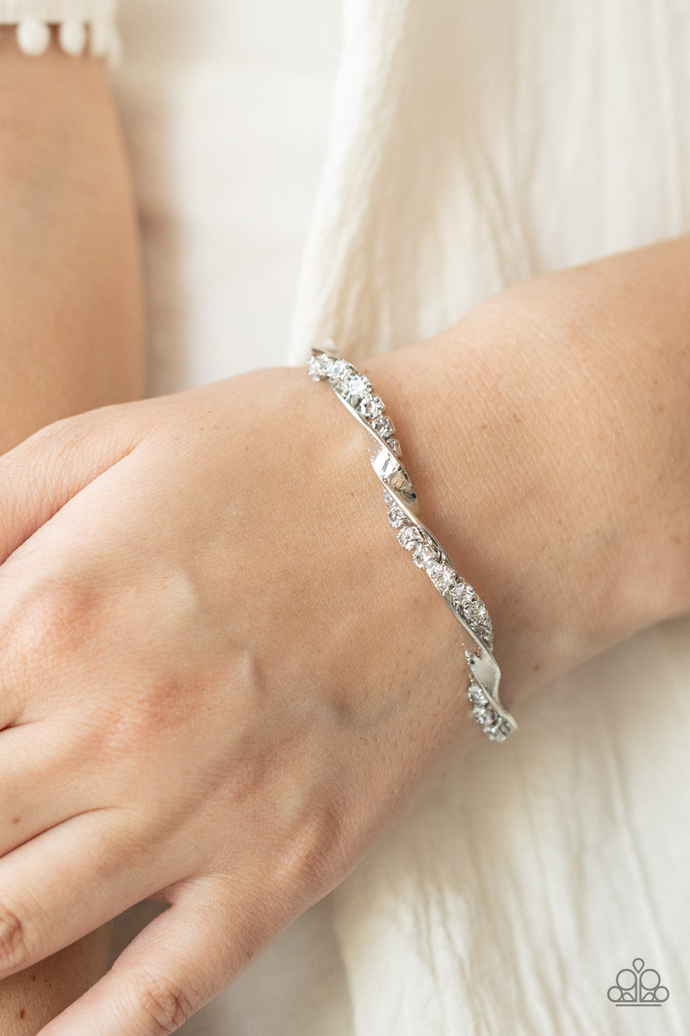 glittery strand of glassy white rhinestones twists with a shiny silver bar around the wrist, creating a dainty cuff.