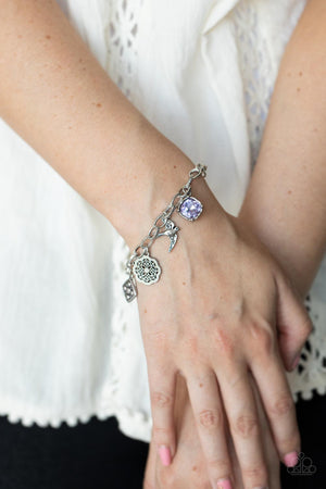 Sparkling purple gems, a floral medallion, a bird in flight, and a fluttering feather dangle from a delicate silver chain