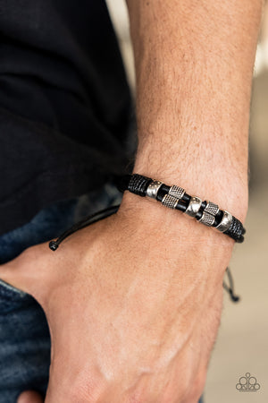 Shiny and textured silver cylindrical accents slide along a double layer of thick black leather cording