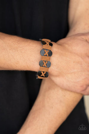 Light brown suede cording is threaded in a crisscross pattern along the front of a wavy brown suede band