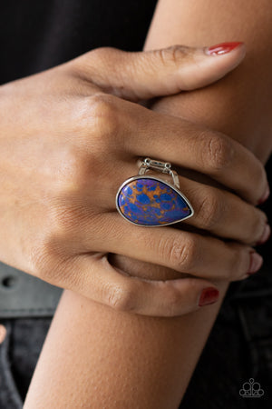 polished blue stone infused with veins of brown and purple is encased in a simple silver teardrop frame