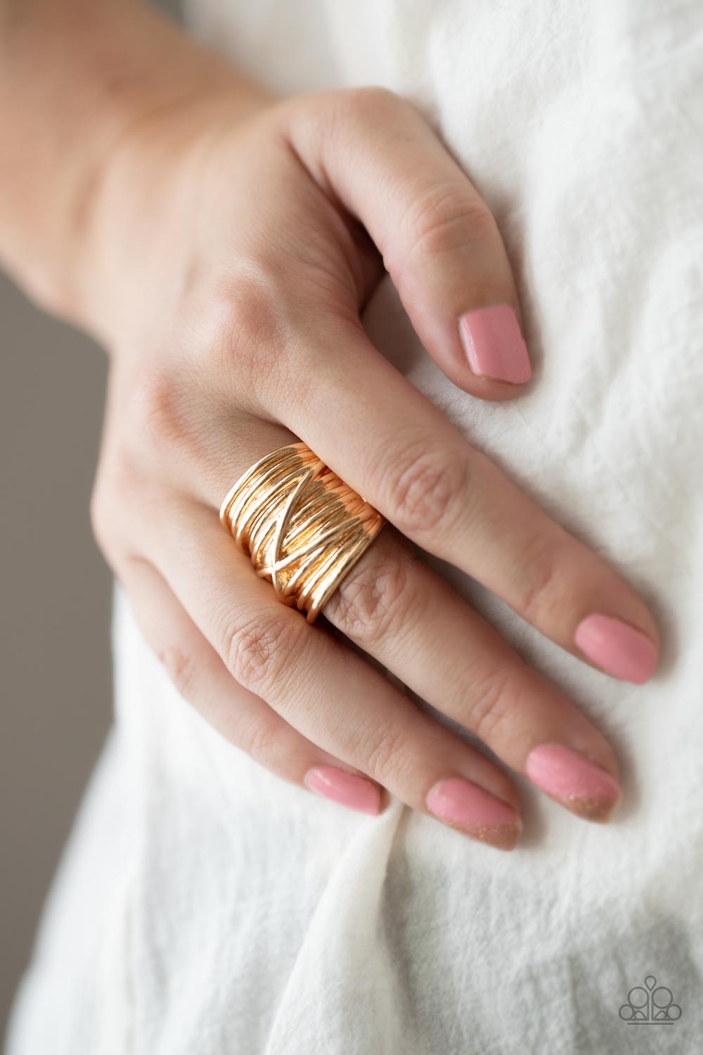 Row after row of glistening gold bars delicately crisscross and overlap across the finger, coalescing into faux layers across the finge