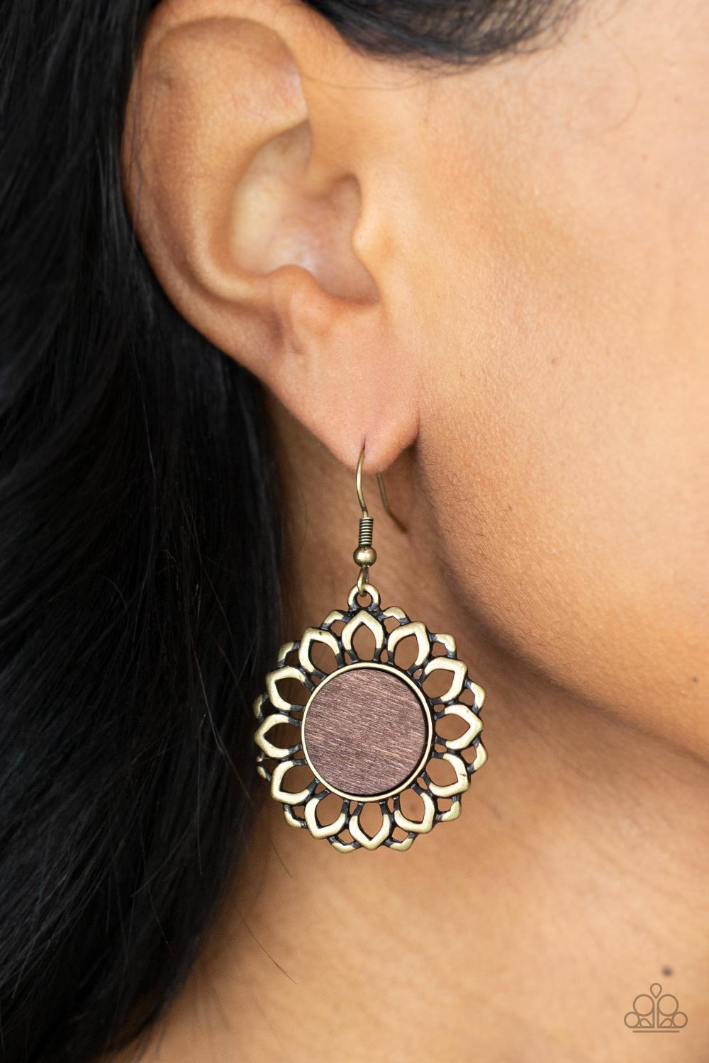 Layers of antiqued brass petals bloom from a flat brown wooden center
