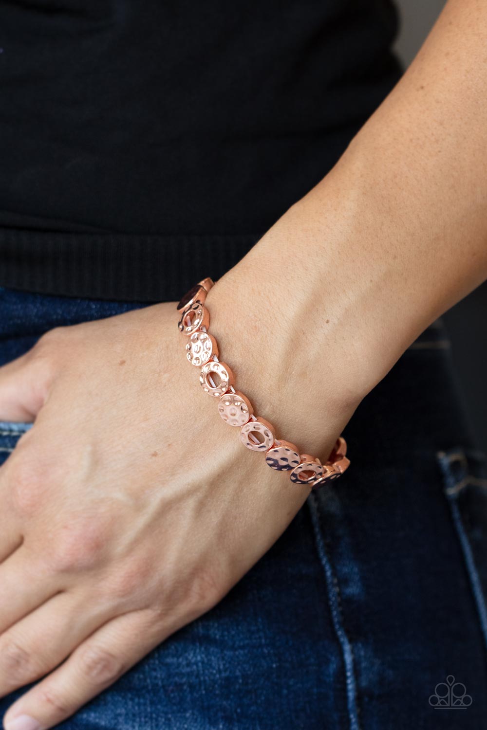 hammered collection of shiny copper rings and discs are threaded along stretchy bands