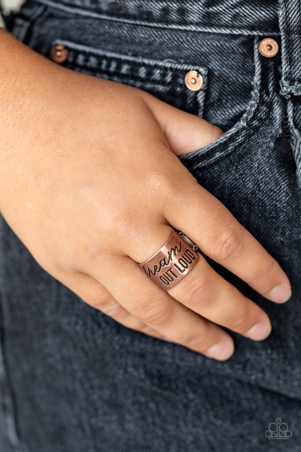 The front of a thick copper band is stamped in the phrase, "Dream out loud," creating an inspirational centerpiece across the finger.