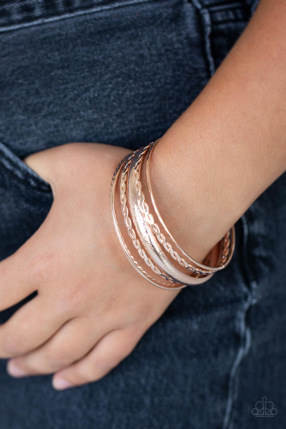polished finish, a mismatched collection of textured, braided, hammered, and plain rose gold bangles 