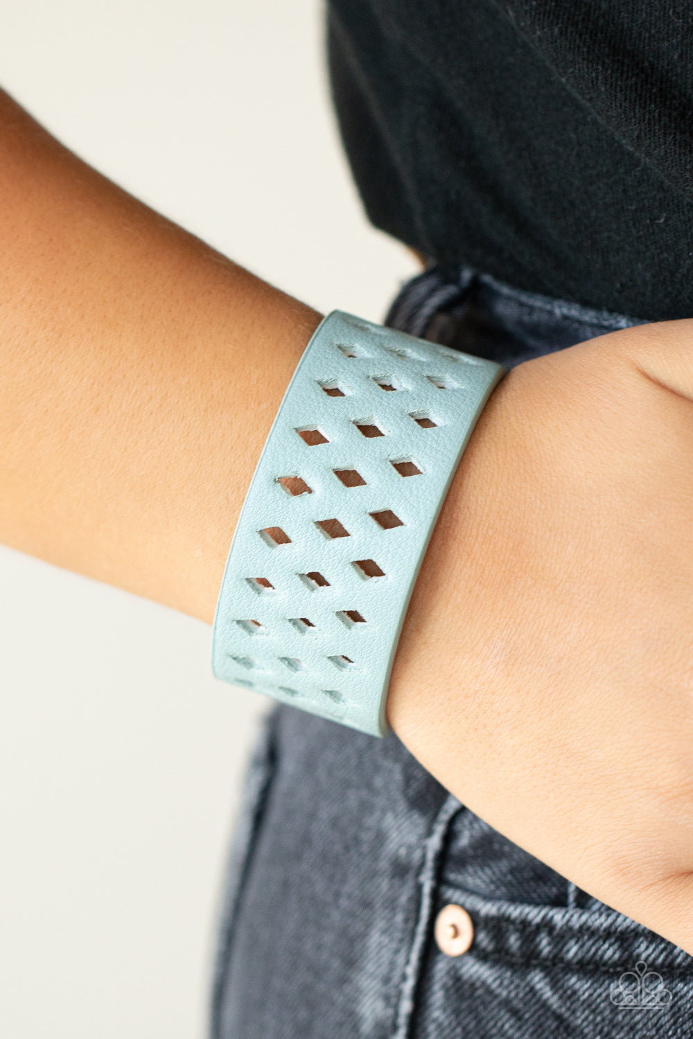 wide blue leather band is filled with patterned rows of small diamond-shaped cutouts giving the illusion of diamonds floating across the wrist