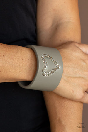 The center of an Ultimate Gray leather cuff is studded in a charming heart pattern, creating a rustically romantic look around the wrist.