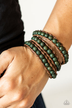 green wooden beads are knotted in place along two brown leather cords, creating multiple earthy layers around the wrist