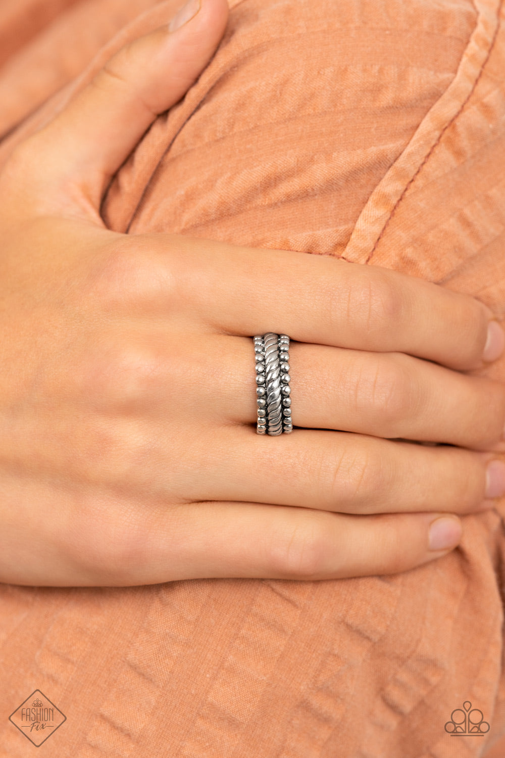 A twisted silver band is flanked by rows of antiqued silver studs, creating a rustically layered look across the finger