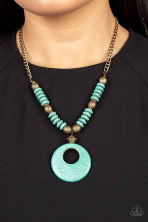 Infused with dainty brass accents, mismatched brass beads and turquoise stone discs are threaded along an invisible wire below the collar. An oversized turquoise stone pendant swings from the center of the earthy strand