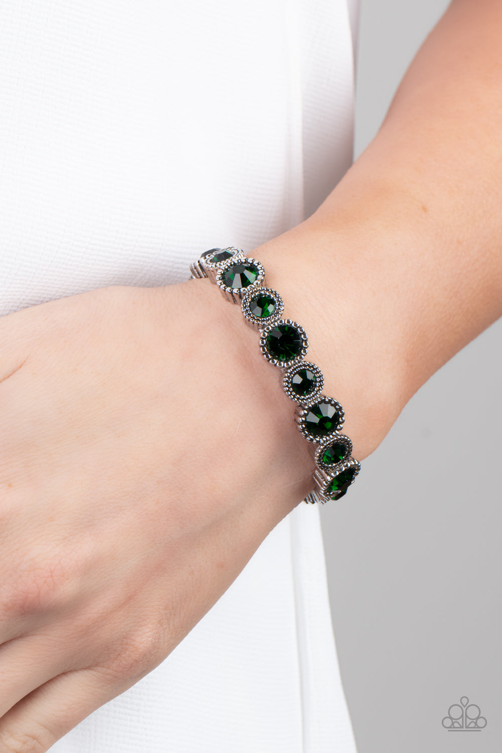 Sparkling green gems are encased in studded silver frames
