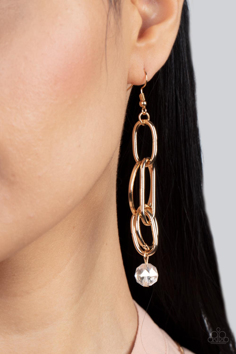 A collection of oval and round gold links, embellished with a faceted white bead suspended inside the bottom-most round frame, coalesce into a flirty charm as it sways from the ear. Earring attaches to a standard fishhook fitting.