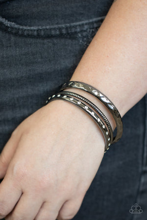 gunmetal bangle that is embossed and faceted in an edgy geometric pattern joins a mismatched pair of white rhinestone encrusted and diamond cut gunmetal bangles 