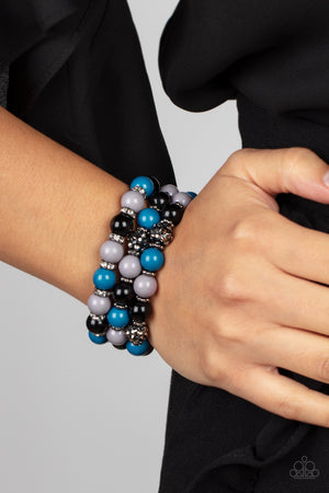  posh collection of polished multicolored beads, studded gunmetal rings, white rhinestone encrusted rings, and hematite dotted beads are threaded along stretchy bands around the wrist