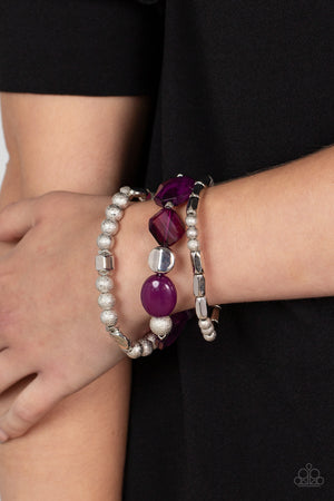 Infused with vivacious pops of plum crystal-like and glassy accents, a mismatched assortment of hammered, cube, and faceted silver beads are threaded along stretchy bands around the wrist