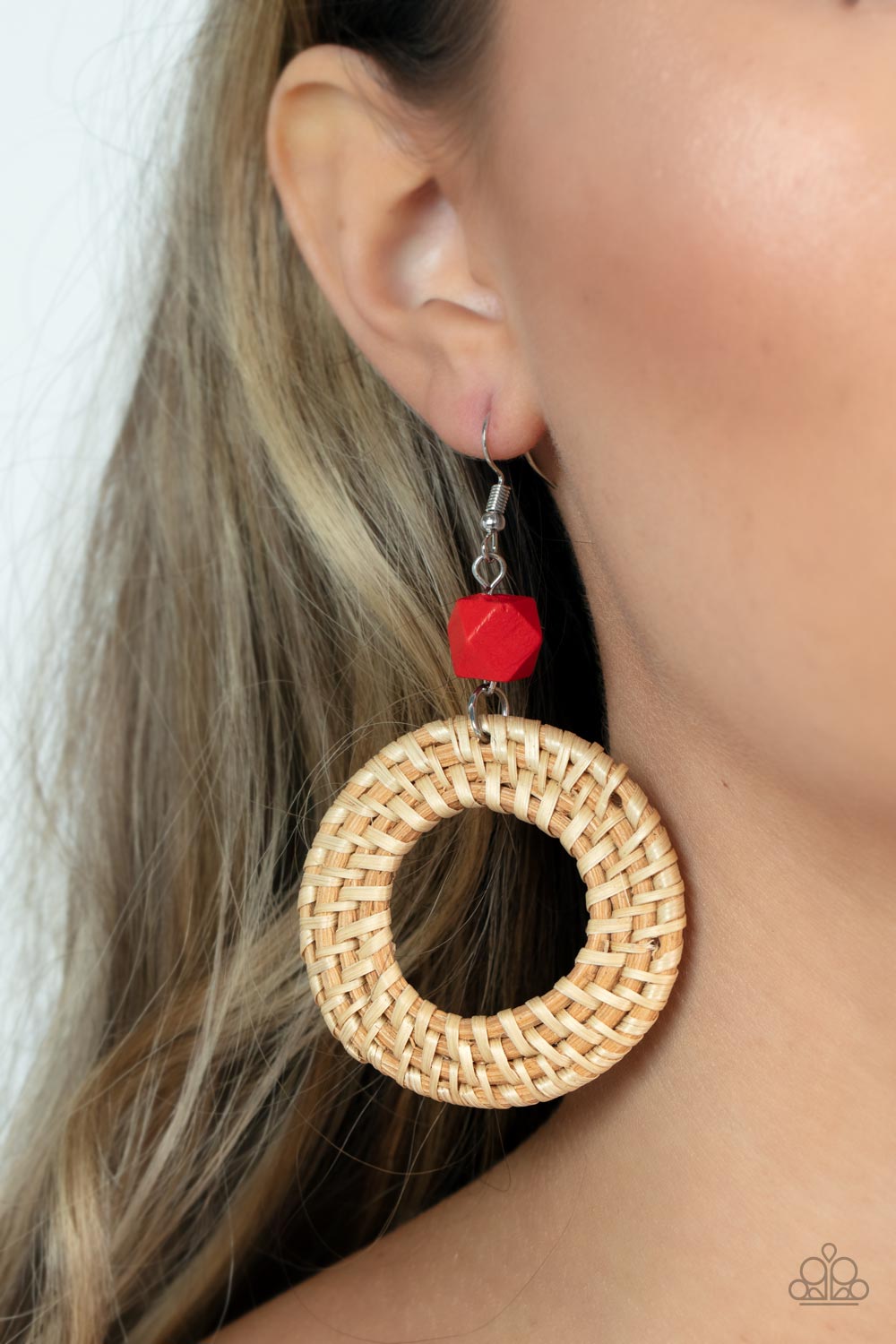 A wicker-like hoop swings from the bottom of a faceted red wooden bead, adding an earthy twist to the trendy homespun trinket