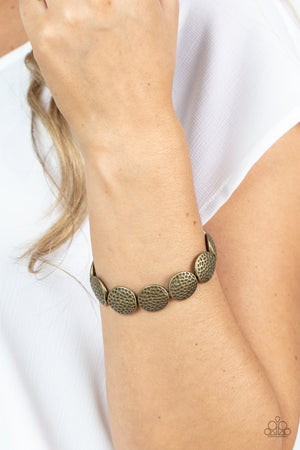 Hammered in antiqued details, a rustic collection of brass beads are threaded along a stretchy band around the wrist for a wildly adventurous look.