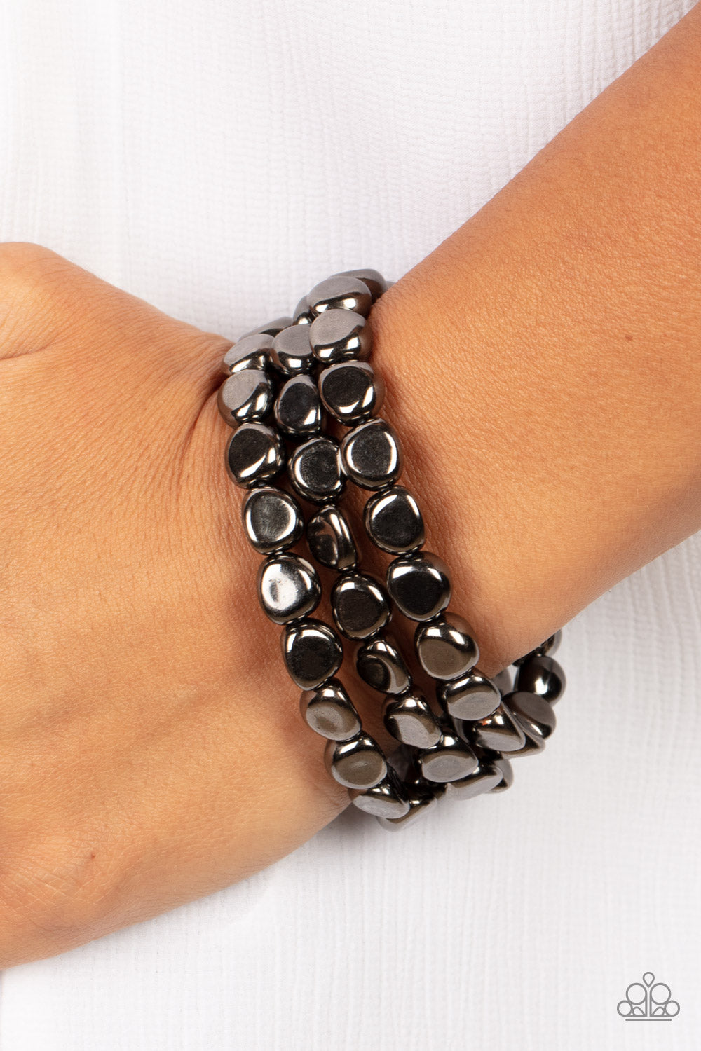 Featuring irregular stone shapes, a shiny series of gunmetal beads are threaded along stretchy bands