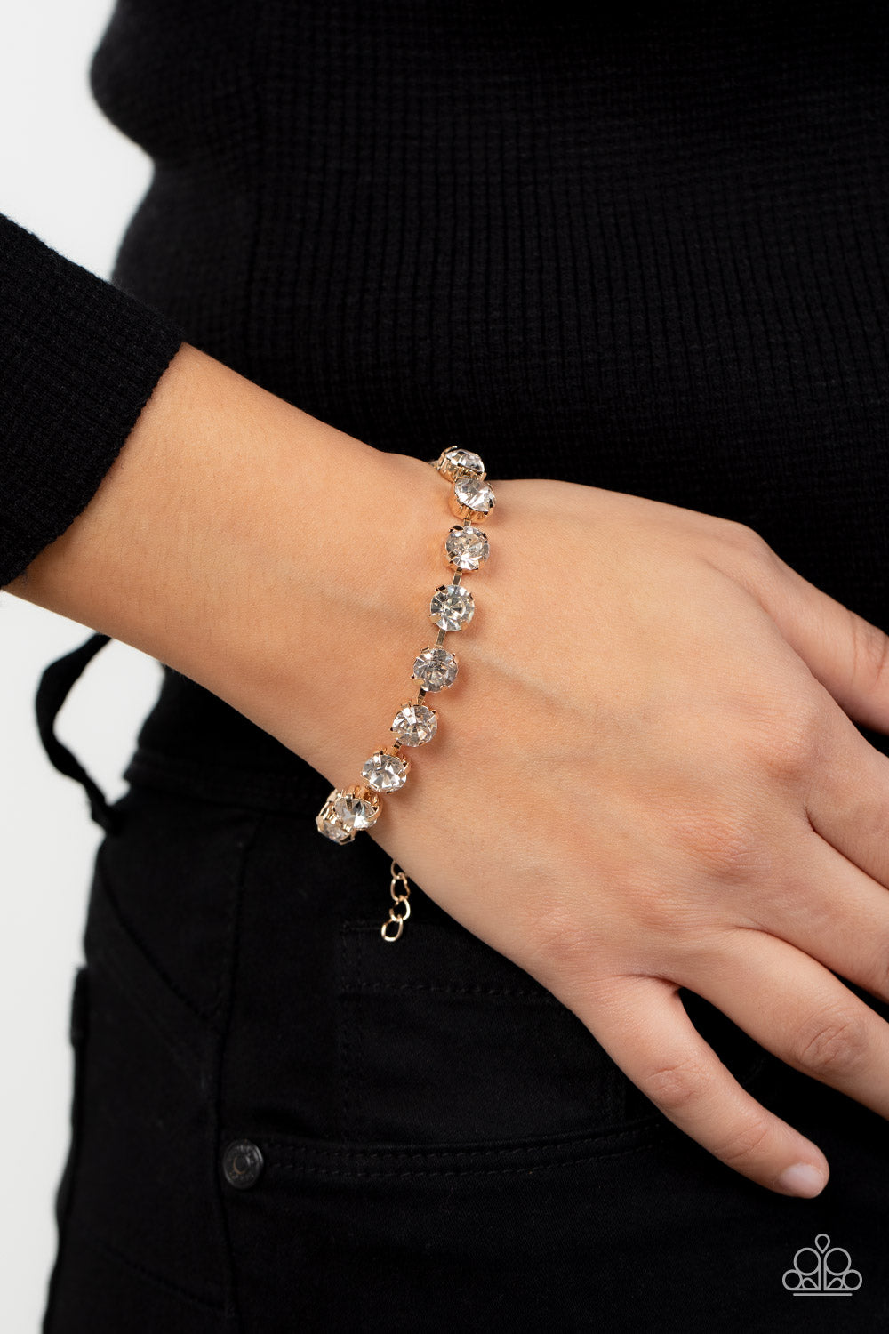 pronged gold fittings, an oversized row of glassy white rhinestones connect around the wrist