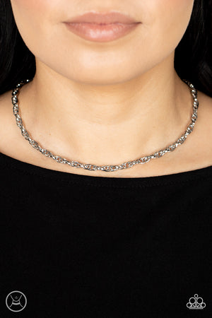 An ornately linked silver chain wraps around the neck, resulting in an edgy minimalist inspired grit