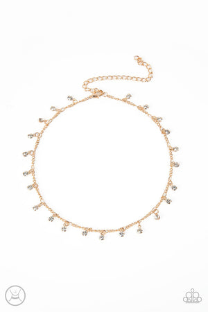Glassy white rhinestones swing from a dainty gold chain around the neck