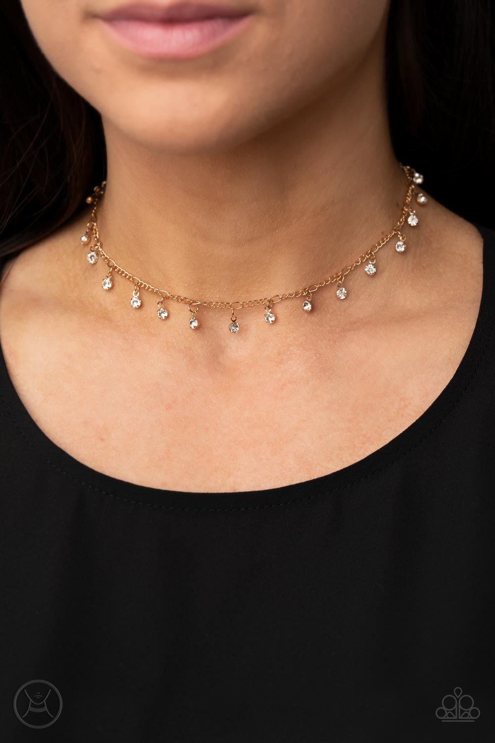 Glassy white rhinestones swing from a dainty gold chain around the neck