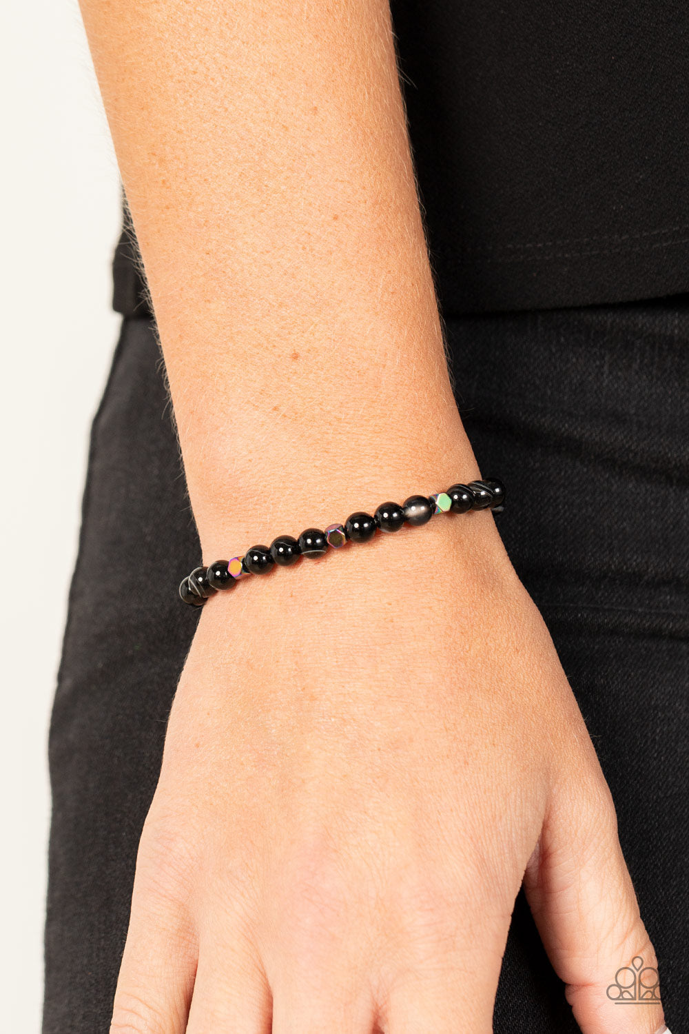 A dainty collection of natural-finished black stone beads and faceted metallic oil spill cube beads are threaded along a stretchy band