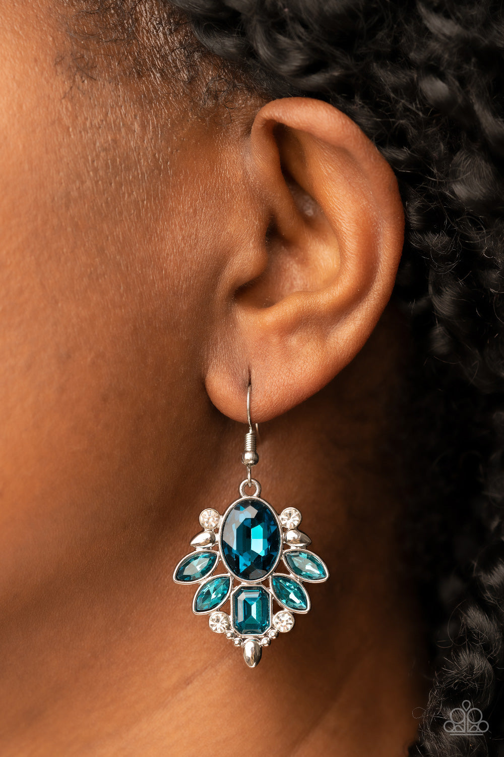 brilliant blue gem makes a sparkling centerpiece amidst a glitzy fringe of marquise and emerald-cut blue rhinestones