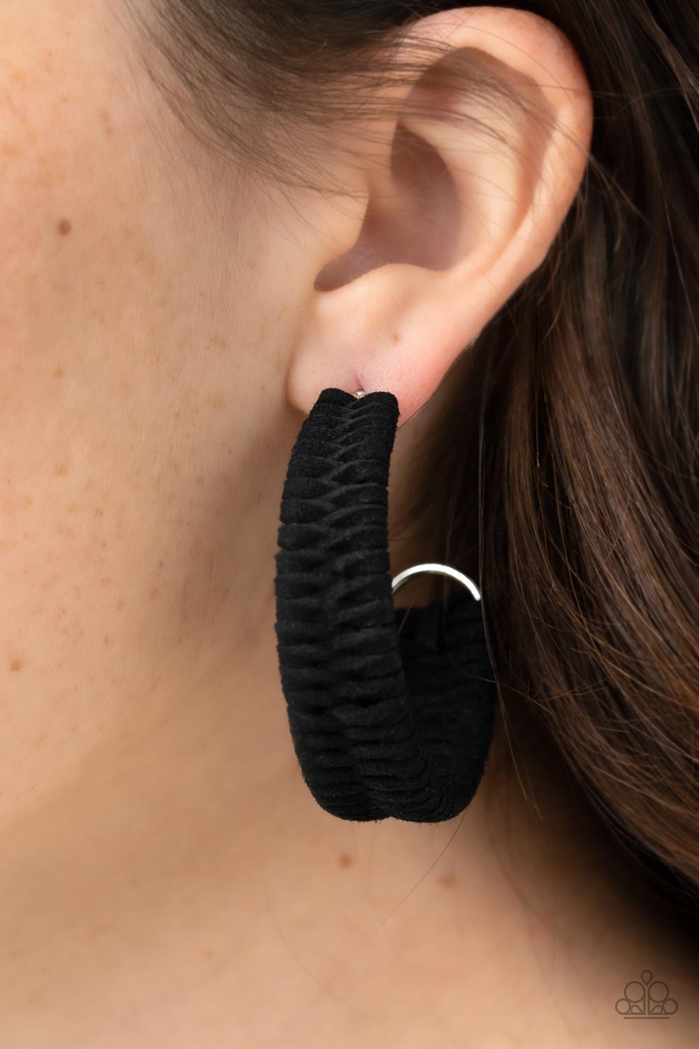Black suede cording crisscrosses around a layered silver frame that widens as it curves into a simple hoopBlack suede cording crisscrosses around a layered silver frame that widens as it curves into a simple hoop