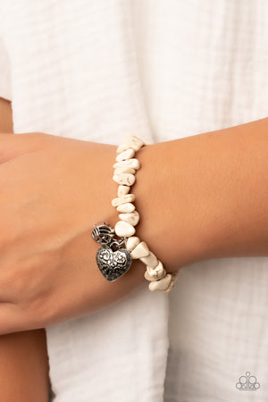 Infused with a hammered silver bead and decorative silver heart charm, an earthy collection of white pebbles are threaded along a stretchy band around the wrist