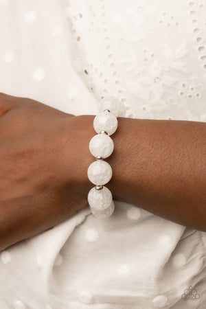 Infused with dainty silver accents, an oversized collection of crackly white glass-like beads are threaded along stretchy bands