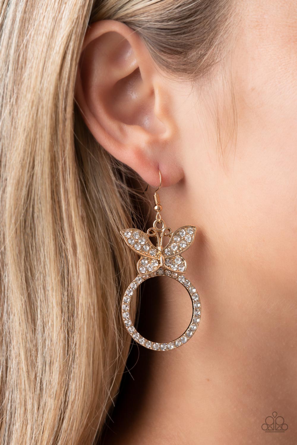 A white rhinestone encrusted gold butterfly flutters atop a gold ring dotted in matching white rhinestones