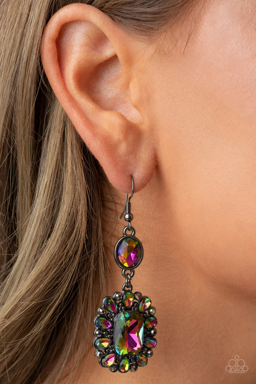 Dainty hematite rhinestones and teardrop oil spill gems fan out from an oversized oil spill emerald cut gem at the bottom of a solitaire oval oil spill gem