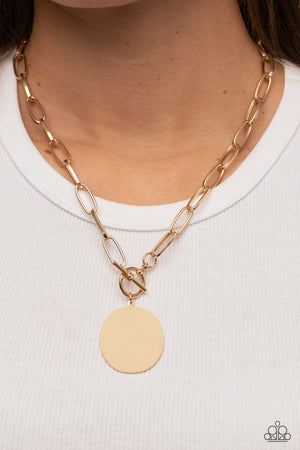 oversized oval gold disc swings from the bottom of a substantial oval linked gold chain