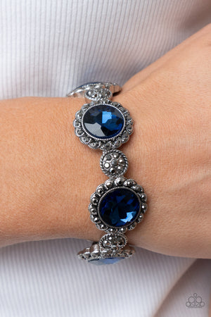 oversized blue rhinestone adorns the center of a hematite rhinestone petaled floral frame. Infused with hematite dotted silver accents