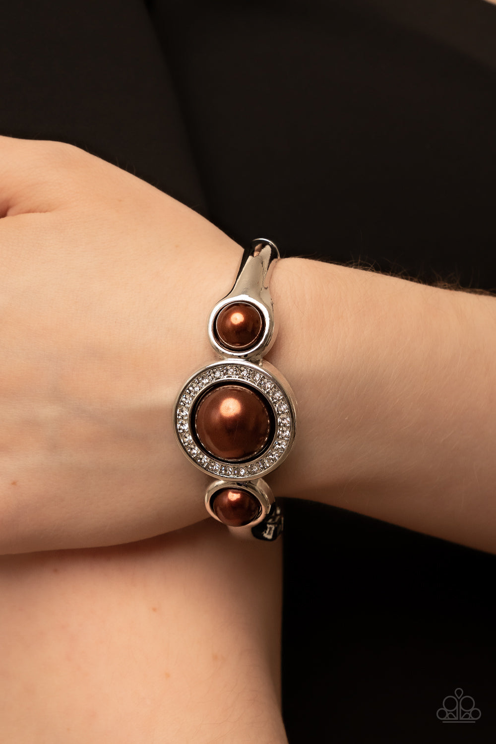 glitzy ring of glassy white rhinestones, oversized brown pearl 