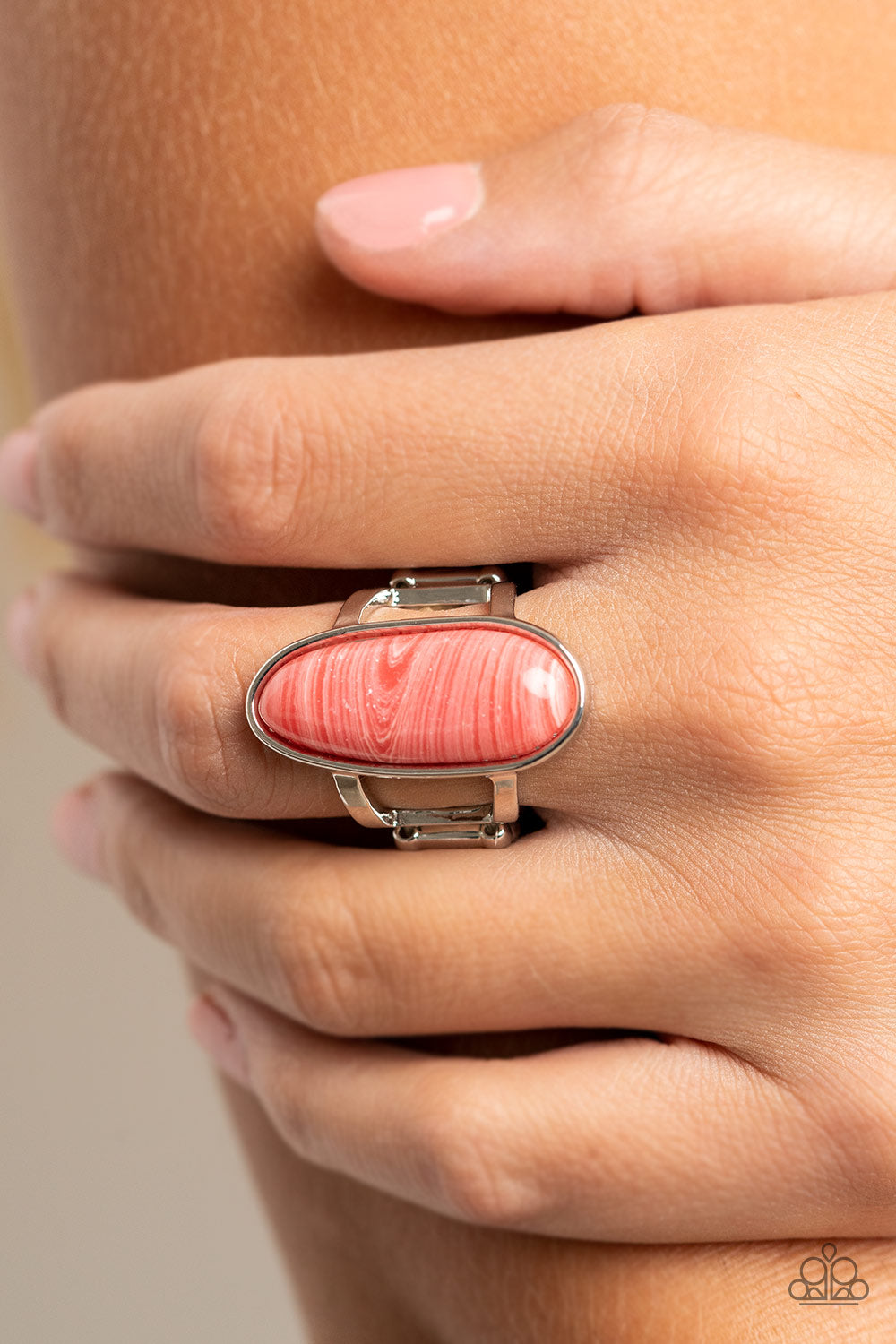 faux sandstone finish, an oblong pink bead is pressed into a sleek silver fitting atop layered silver bands