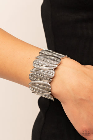 Embossed in feather-like details, pairs of overlapping silver leaf frames are threaded along stretchy bands around the wrist