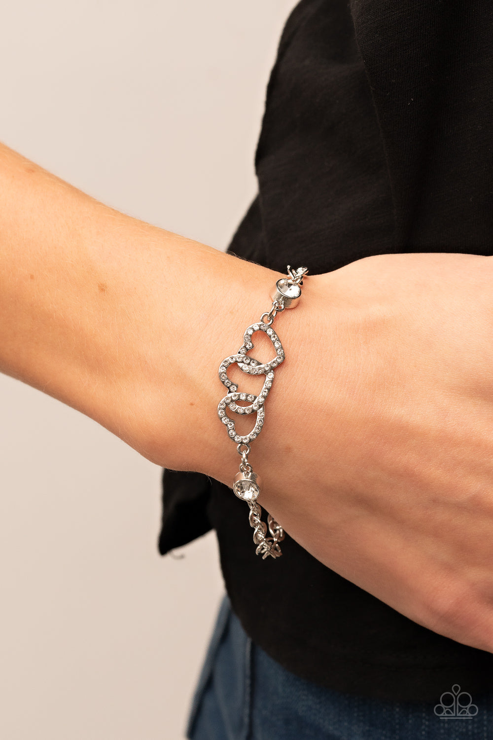 White rhinestone dotted hearts delicately interlock between two white rhinestone fittings, creating heart-pounding sparkle atop the wrist