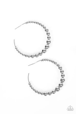 Gradually increasing in size, shiny silver beads are threaded along an oversized silver hoop