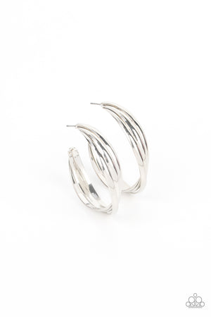 Flat silver bars delicately twist and overlap into an oversized hoop, creating an edgy shimmer