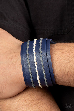 Three rows of gray and white cording are laced down the center of a blue leather band that is studded in place across the front of a thick blue leather band