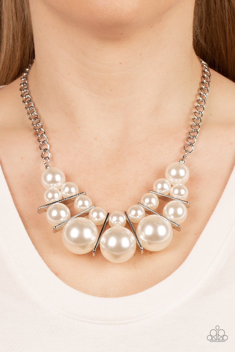 Separated by rectangular silver frames, bubbly rows of classic and oversized white pearls are threaded along invisible wires at the bottom of a chunky silver chain 