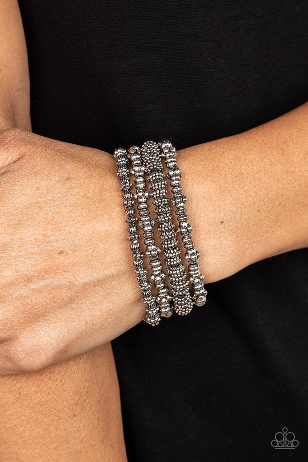 antiqued assortment of studded, round, and decorative silver beads are threaded along stretchy bands around the wrist