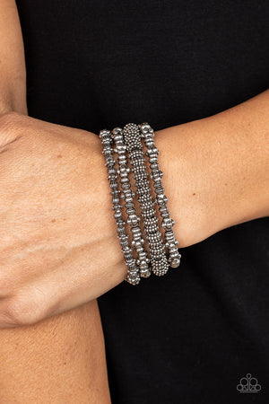 antiqued assortment of studded, round, and decorative silver beads are threaded along stretchy bands around the wrist