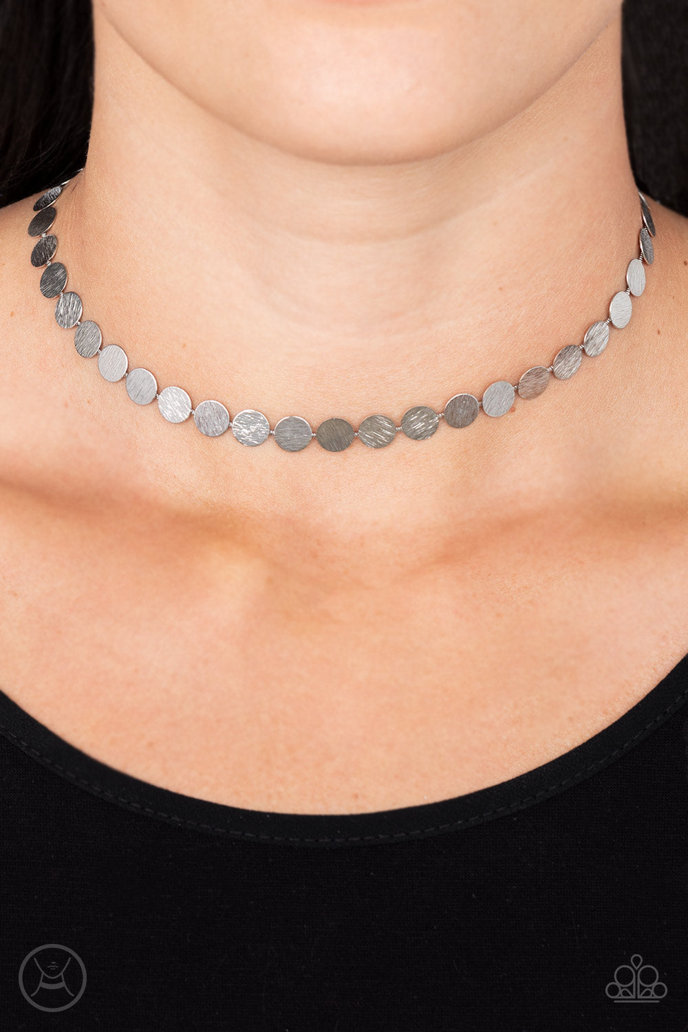 Delicately scratched in blinding shimmer, a row of dainty silver discs shines around the neck