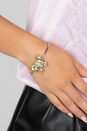 silver butterfly with yellow teardrop rhinestone wings and a white-rhinestone body delicately perches atop a shiny silver cuff